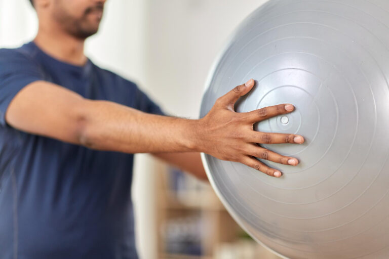 Bobath Physiotherapie in Fürth: Patient übt Gleichgewicht und Armführung mit dem Gymnastikball