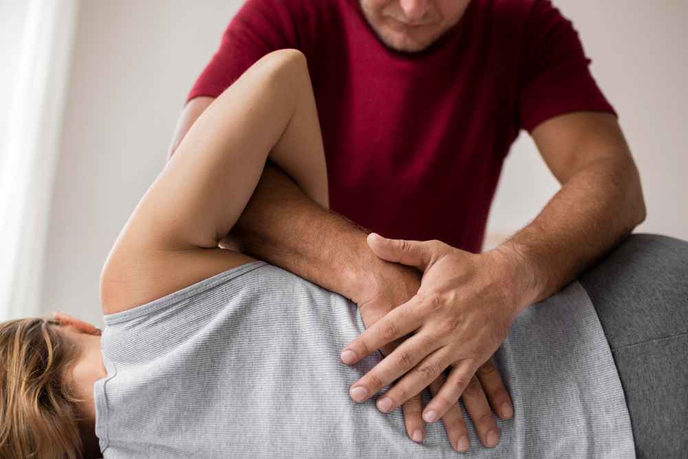 Manuelle Therapie in Fürth: Physiotherapeut mobilisiert Schulter und Schulterblatt einer Patientin